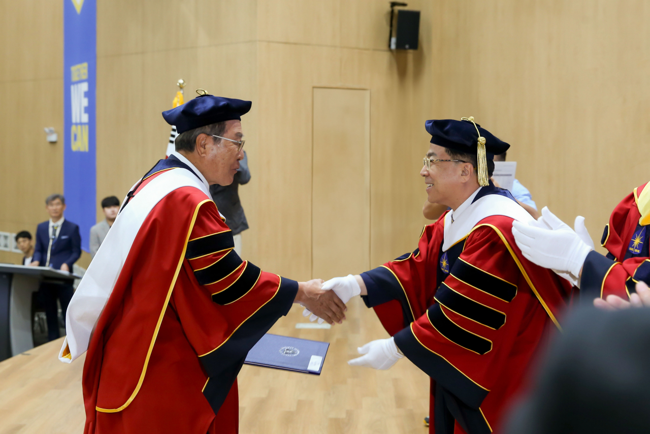 윤동한 한국콜마 회장(사진 왼쪽)이 지난 22일 경북 경산시에서 열린 대구가톨릭대 학위수여식에서 문학박사 학위를 받고 성한기 대구가톨릭대 총장(사진 오른쪽)과 악수하고 있다. [한국콜마 제공]