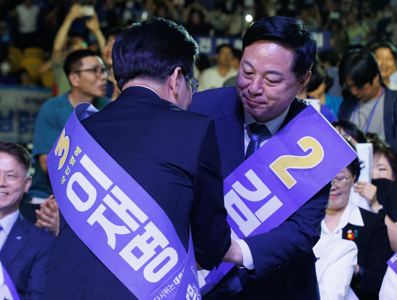 더불어민주당 당대표 연임이 확정된 이재명 당대표(왼쪽)가 18일 오후 서울 송파구 올림픽공원 KSPO돔에서 열린 전국당원대회에서 개표결과가 발표되자 김두관 후보에게 인사를 받고 있다. [연합]