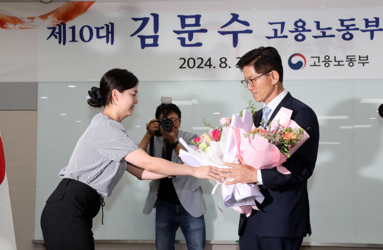 김문수 신임 고용노동부 장관이 30일 오후 정부세종청사 고용노동부 대회의실에서 열린 취임식에서 직원 대표로부터 축하 꽃다발을 받고 있다. [연합]