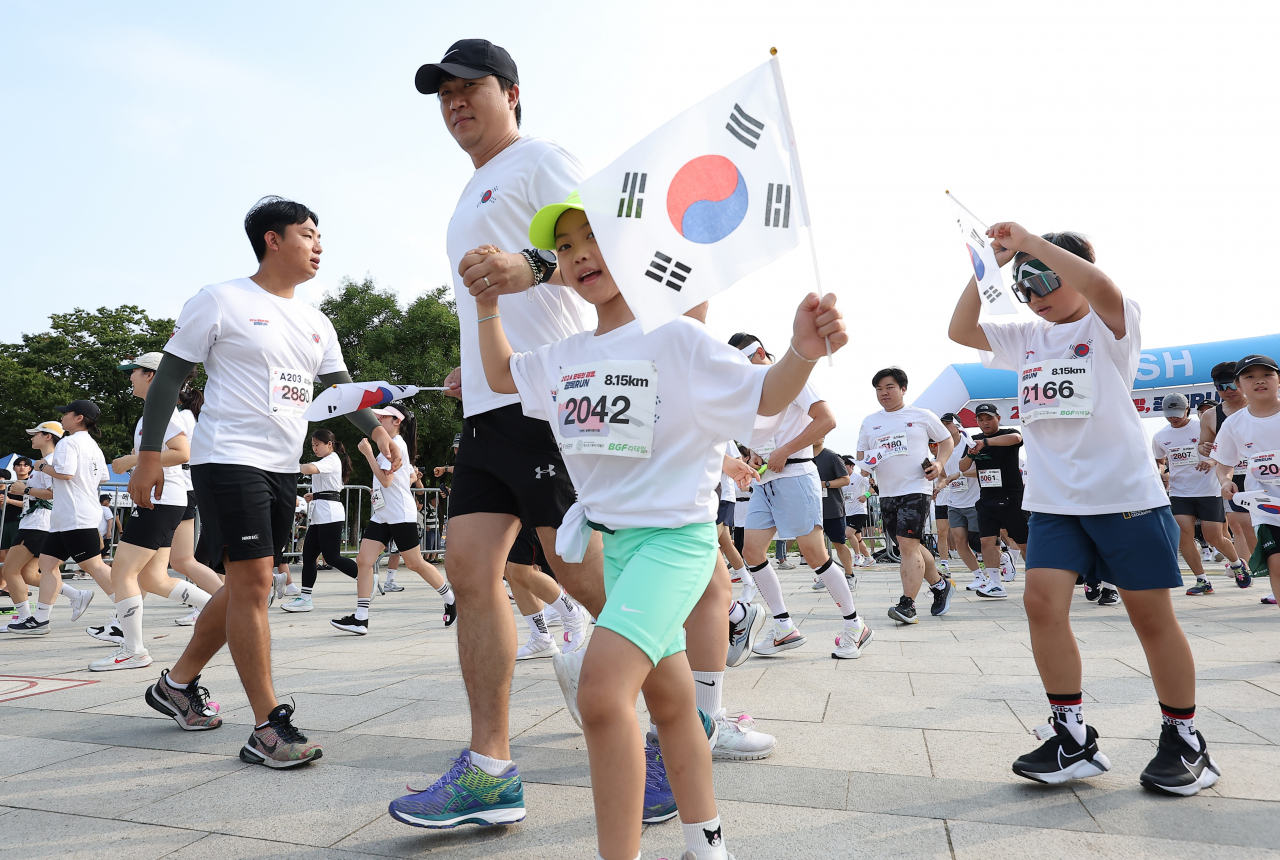 국가보훈부가 지난달 15일 서울 영등포구 여의도한강공원에서 연 광복RUN 달리기 행사에서 시민들이 태극기를 들고 뛰고 있다. 이날 션 역시 광복절을 기념해 다른 곳에서 ‘81.5㎞ 기부 마라톤’을 펼쳤다. [연합]