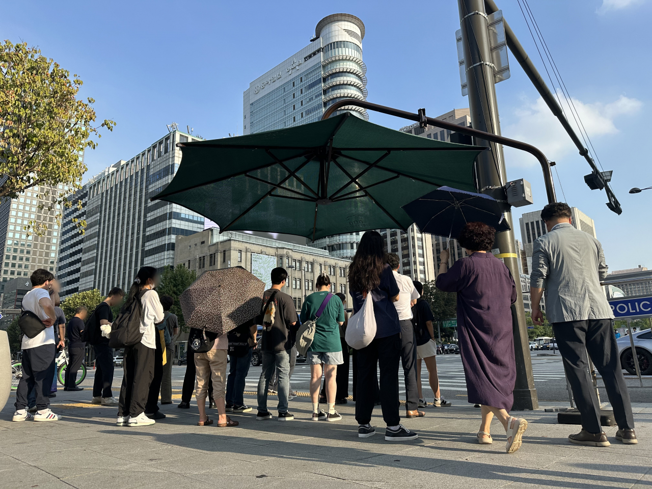 서울 전역에 폭염 경보가 발효된 10일 오후 서울 종로구 세종로 사거리에서 시민들이 그늘막 아래에서 더위를 피하며 신호를 기다리고 있다. [연합]