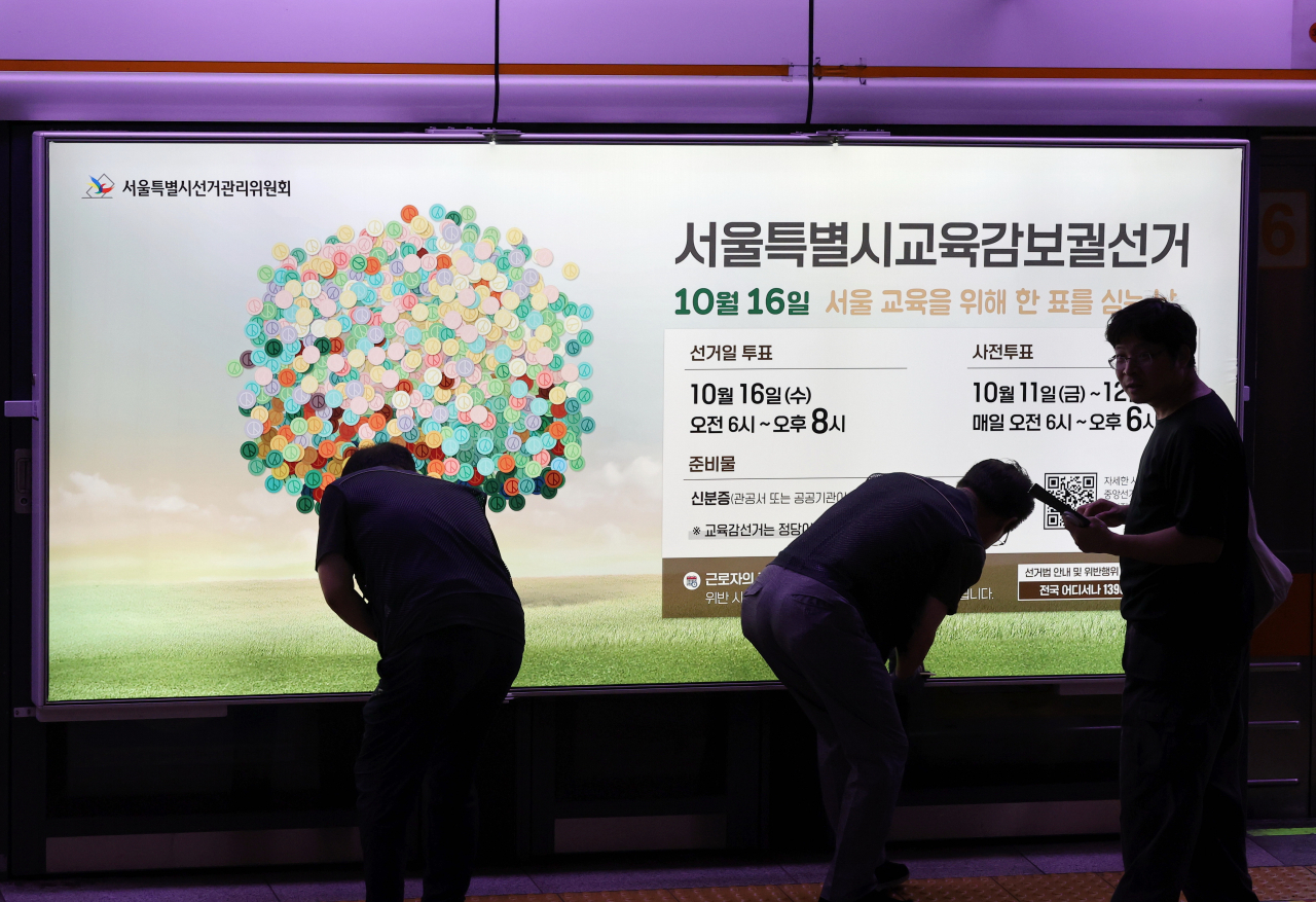 13일 오전 서울 지하철 3호선 충무로역 승강장 스크린 도어에 선관위 관계자들이 오는 10월 16일 실시하는 서울시교육감 보궐선거 홍보물을 부착하고 있다. [연합]
