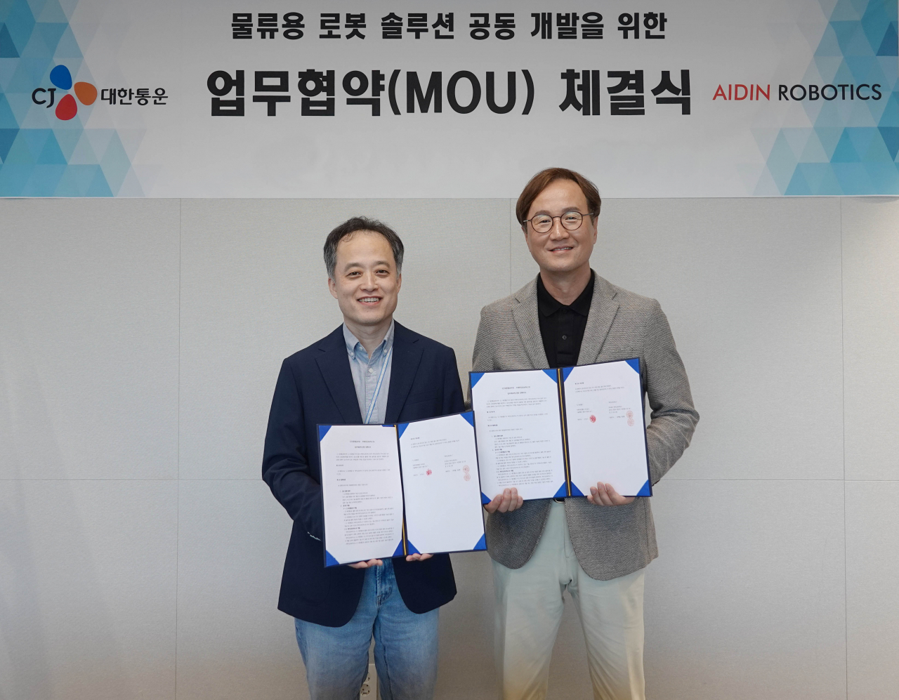 24일 CJ대한통운 본사에서 진행된 MOU 행사에 참여한 CJ대한통운 김정희(왼쪽) TES물류기술연구소장과 에이딘로보틱스 최혁렬 대표가 협약서를 들고 기념사진을 찍고 있다. [CJ대한통운 제공]
