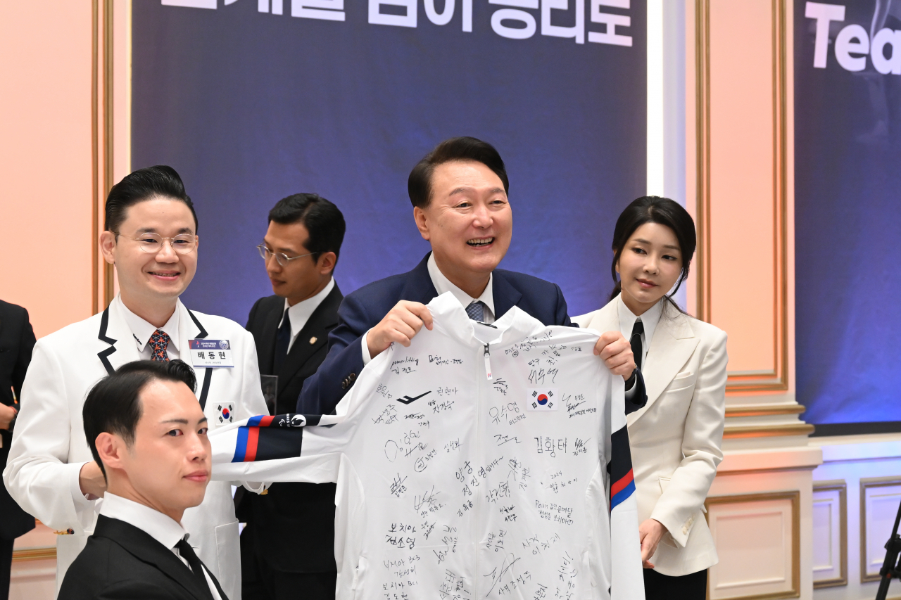 윤석열 대통령과 김건희 여사가 지난 13일 청와대 영빈관에서 열린 '2024 파리 패럴림픽 선수단 격려 오찬'에서 배동현 파리 패럴림픽 선수단장으로부터 패럴림픽 10회 연속 금메달을 달성한 보치아 선수들의 사인이 담긴 선수복을 받고 활짝 웃고 있다. [연합]