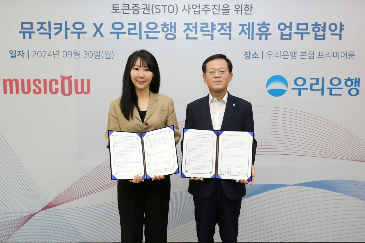우리은행이 지난달 30일 서울 중구 본점에서 뮤직카우와 맺은 업무협약 체결식에서 조병규(오른쪽) 은행장과 정현경 뮤직카우 대표이사가 기념촬영을 하고 있다. [우리은행 제공]