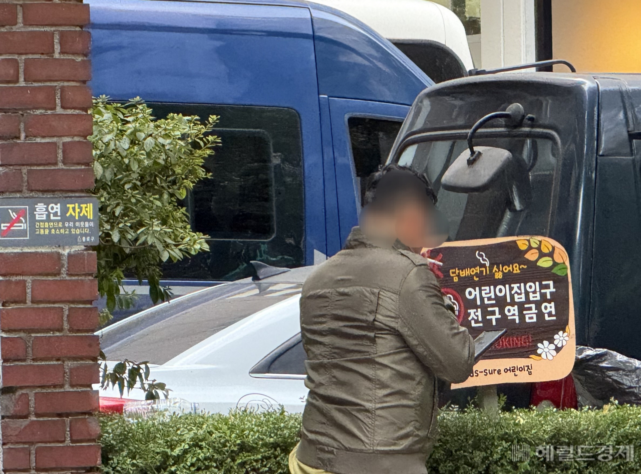 13일 서울시청 인근 어린이집 앞 금연구역에서 한 남성이 흡연을 하며 휴대폰을 보고 있다. 이용경 기자