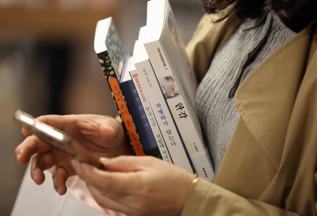 서울 종로구 교보문고 광화문점에서 한 시민이 노벨문학상을 수상한 소설가 한강의 책을 구매하고 있는 모습. [연합]