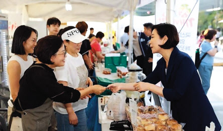 오영주(오른쪽) 중소벤처기업부 장관이 서울 종로구 청계광장에서 열린 ‘동행축제 전통시장 판매전’에서 판매 부스를 둘러보며 제품을 구매하고 있다. [중소벤처기업부 제공]