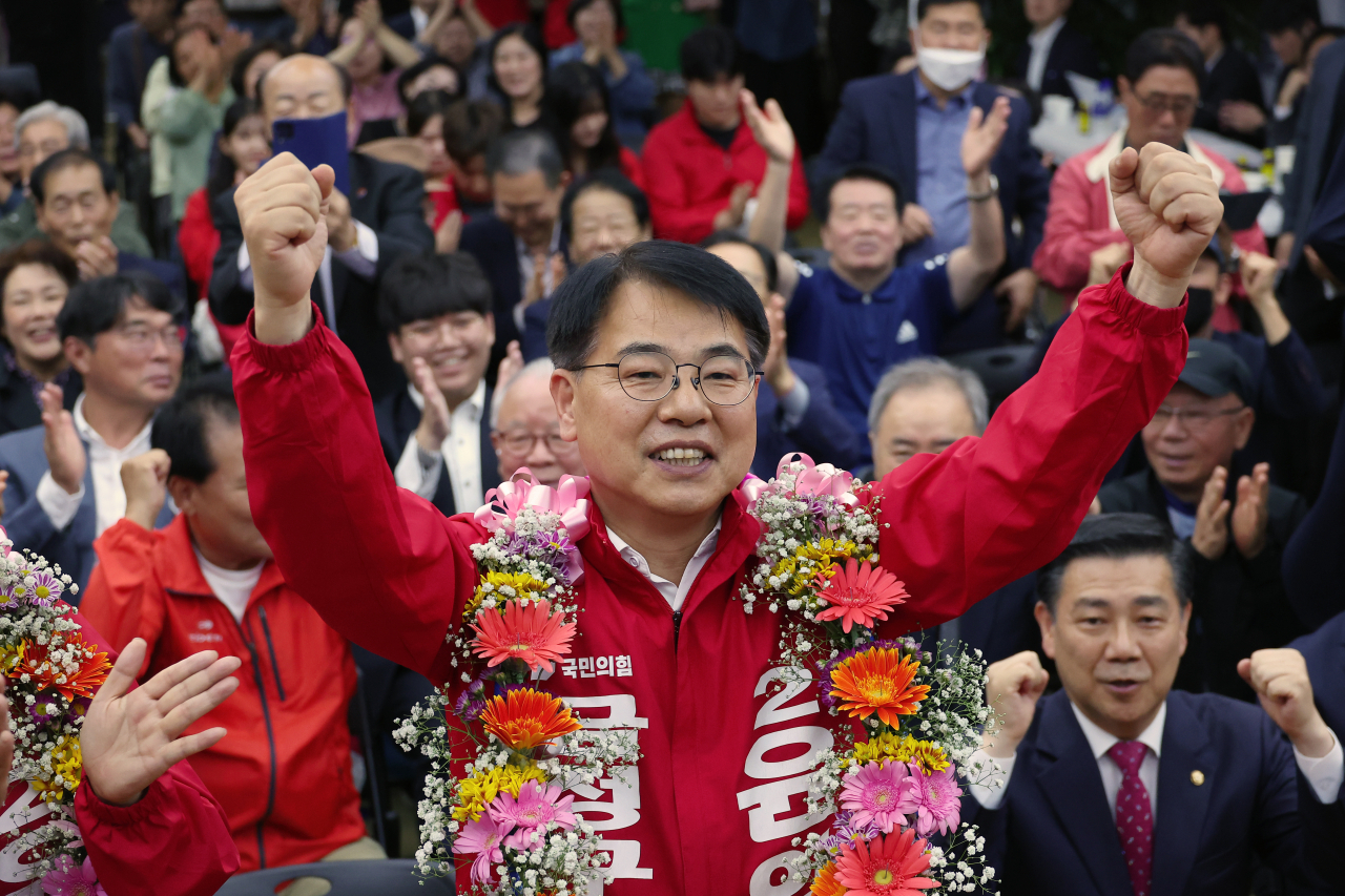 윤일현 국민의힘 금정구청장 보궐선거 후보가 16일 오후 부산 금정구 선거사무소에서 당선이 유력해지자 꽃다발을 걸고 환호하고 있다. [연합]