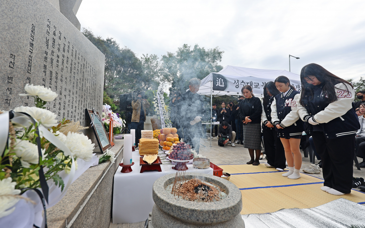 21일 오전 서울 성수대교 북단 위령탑 앞에서 열린 성수대교 붕괴사고 30주기 합동위령제에서 무학여고 학생들이 헌화한 뒤 묵념하고 있다. [연합]