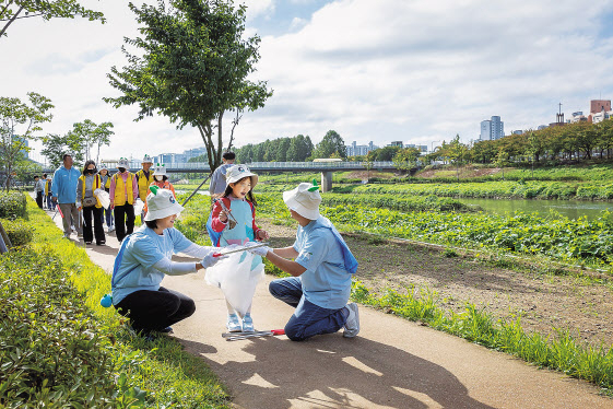 코웨이 임직원과 금천구 자원봉사단이 리버 플로깅 봉사활동을 진행하고 있다. [코웨이 제공]