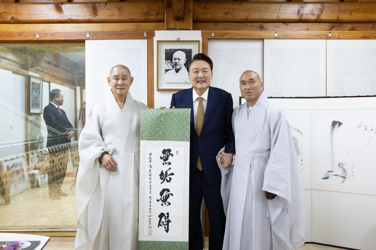윤석열 대통령이 22일 부산 금정구 범어사를 찾아 차담 뒤 주지 정오스님(오른쪽)이 쓴 무구무애(無垢無碍) 족자를 선물 받은 뒤 기념촬영을 하고 있다. 왼쪽부터 방장 정여스님, 윤 대통령, 주지 정오스님. [연합]