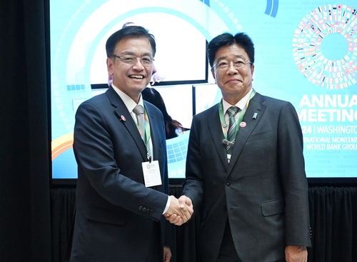 South Korea's Finance Minister Choi Sang-mok (left) shakes hands with Japanese Finance Minister Katsunobu Kato ahead of their meeting in Washington, DC, on Thursday. (The finance ministry)