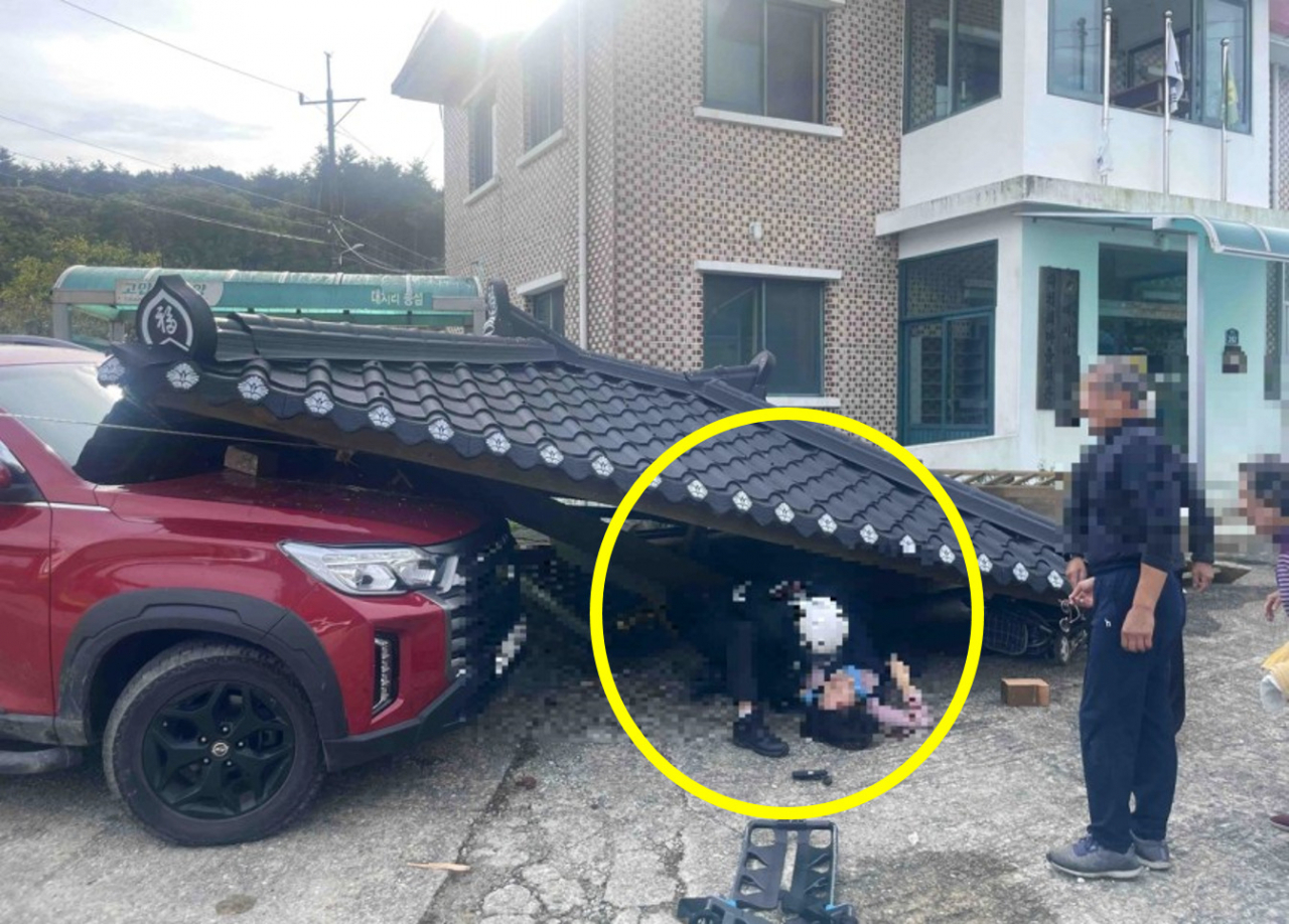 무너진 마을 정자 지붕에 맞아 쓰러진 주민을 구조하는 119. [연합]