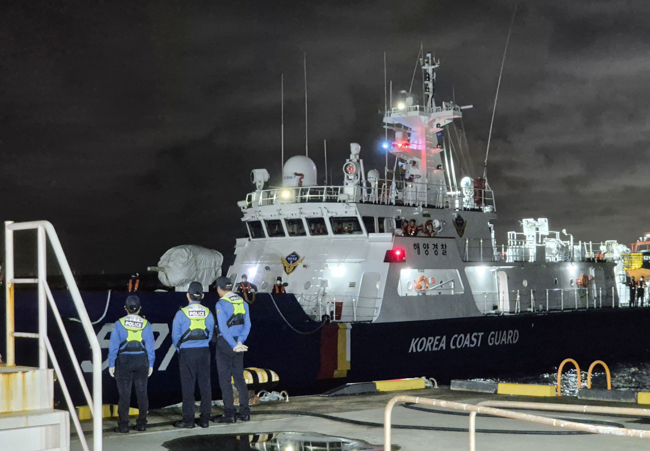 A Coast Guard vessel enters Jeju Harbor at 12:30 a.m. on Monday, carrying the body of a crewmember who died when a fishing boat sank on Friday. (Yonhap)