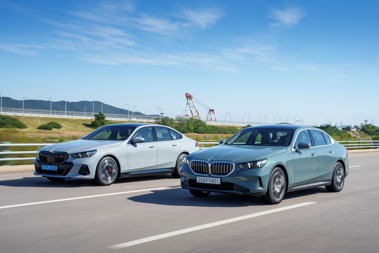 BMW 중형 세단 5시리즈 전동화 모델(왼쪽)과 내연기관 모델이 도로를 달리고 있다. [BMW 제공]