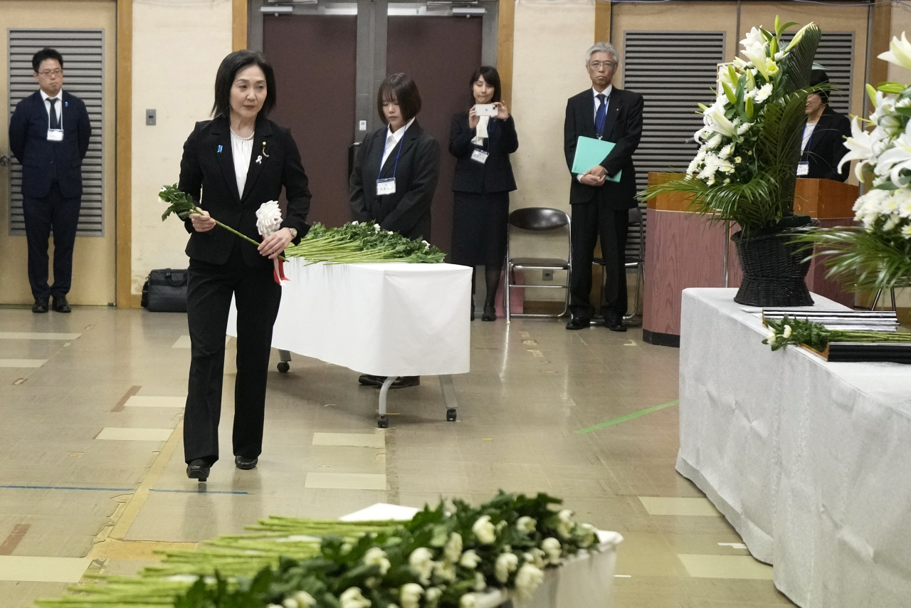 Akiko Ikuina, Parliamentary Vice-Minister for Foreign Affairs, offers a flower on behalf of the government during a memorial ceremony for the Sado Island Gold Mine in Sado, Niigata prefecture, Japan, on Sunday. (AP)