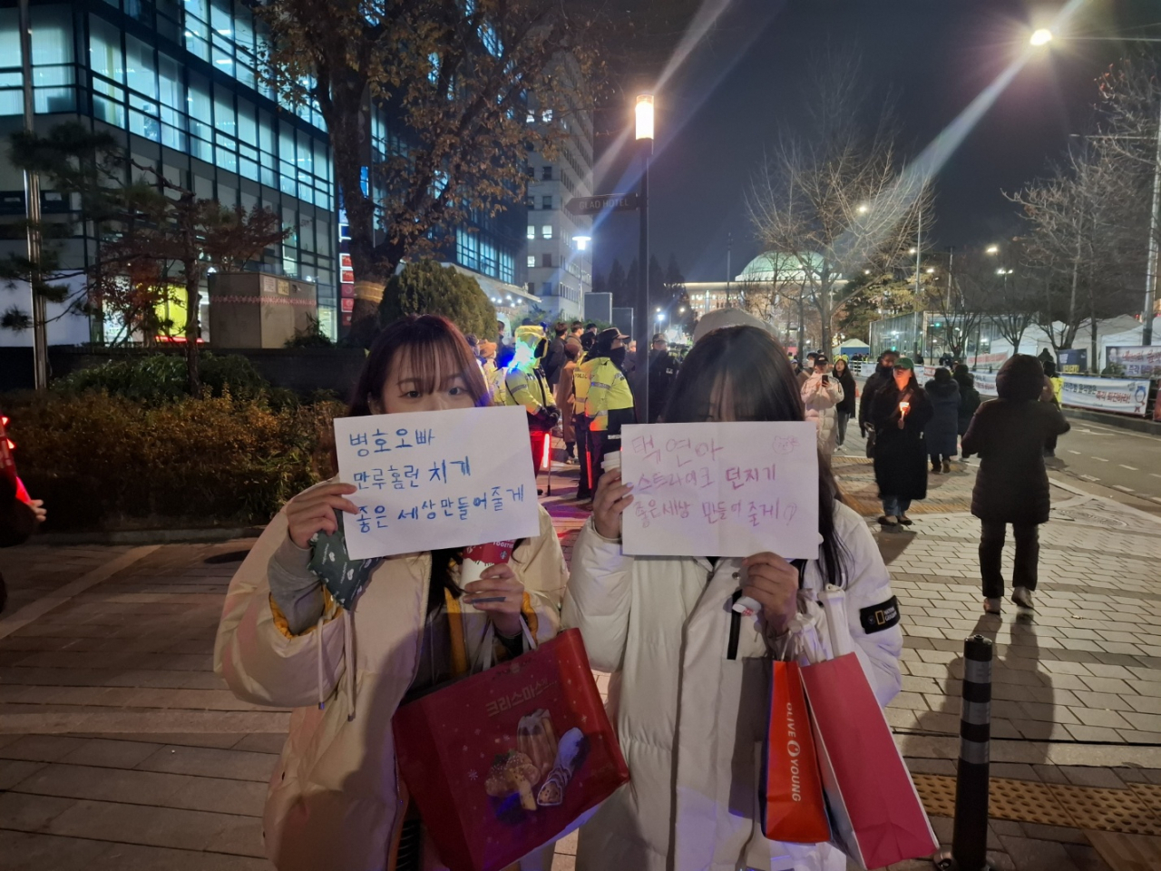 High school seniors Kim Yeon-jung (right) and Seo Su-min show the handmade signs they brought to a rally, having just completed their college entrance exams. (Shin Ji-hye/The Korea Herald)