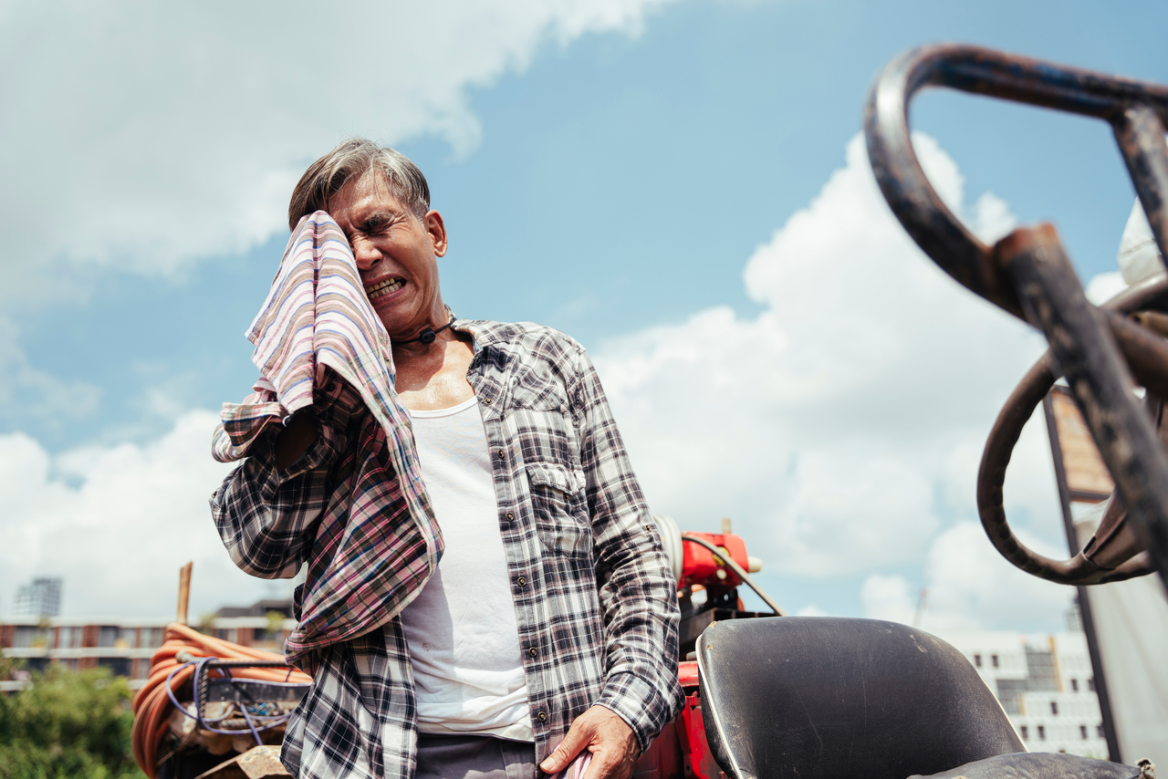 Asian senior farmer resting on a tractor after working at local