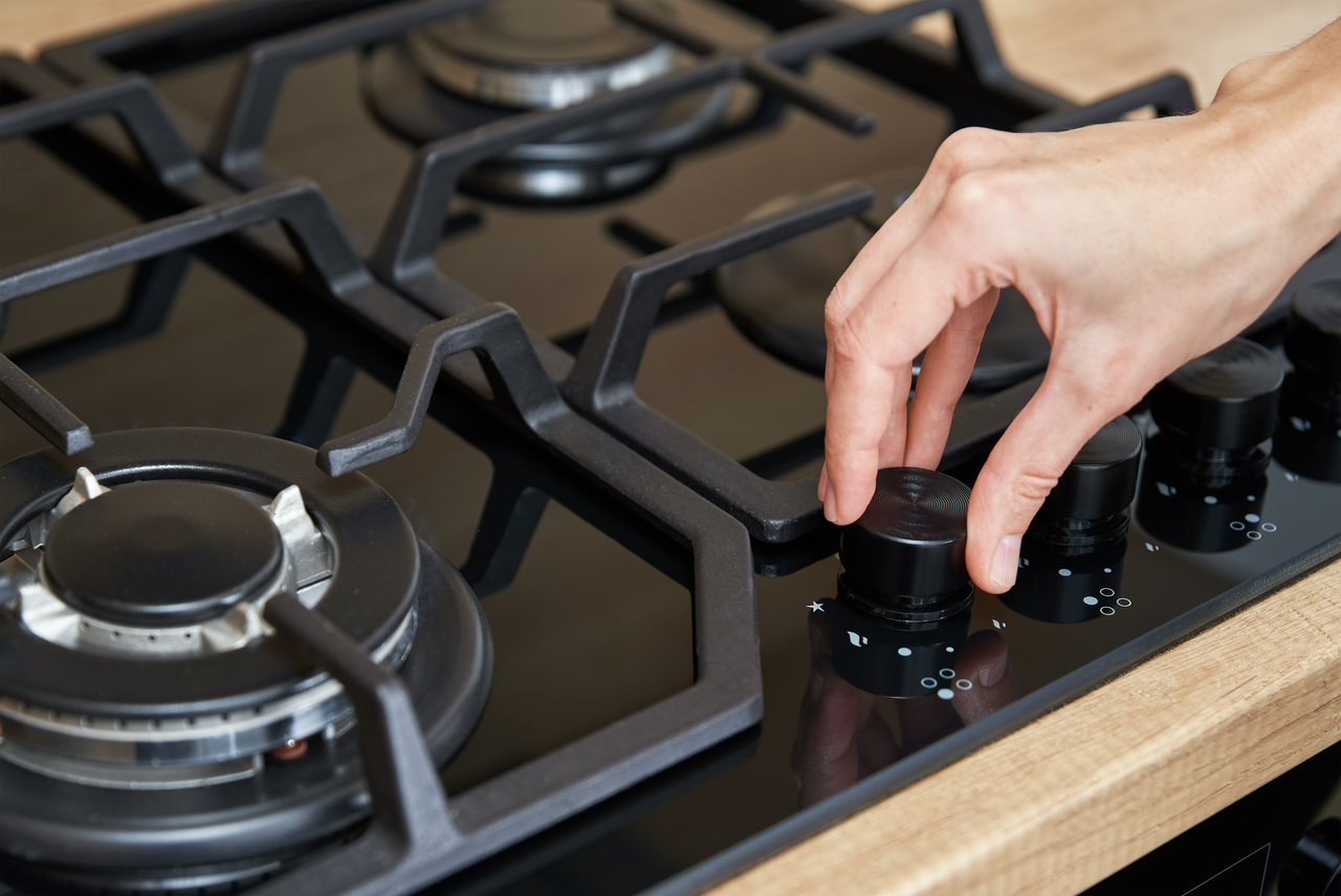 Female hand use gas stove control panel