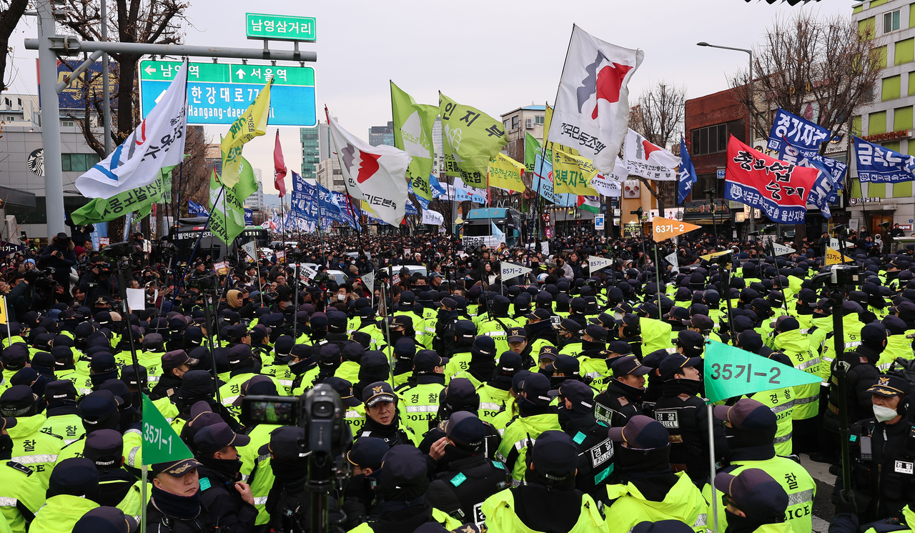 12일 서울 남영삼거리 인근에서 윤석열 대통령 탄핵과 국민의힘 해체를 촉구하며 대통령실 방향으로 행진하던 민주노총 등 단체 회원들이 이를 저지하려는 경찰과 대치하고 있다. [연합]