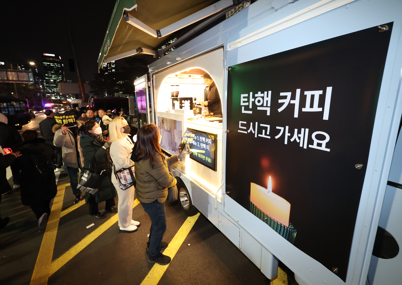 지난 12일 오후 서울 영등포구 국회의사당 인근에서 열린 윤석열 대통령 탄핵 촉구 촛불 집회 행진에 참석한 시민들이 커피차에서 무료 음료를 기다리고 있다. [연합뉴스]