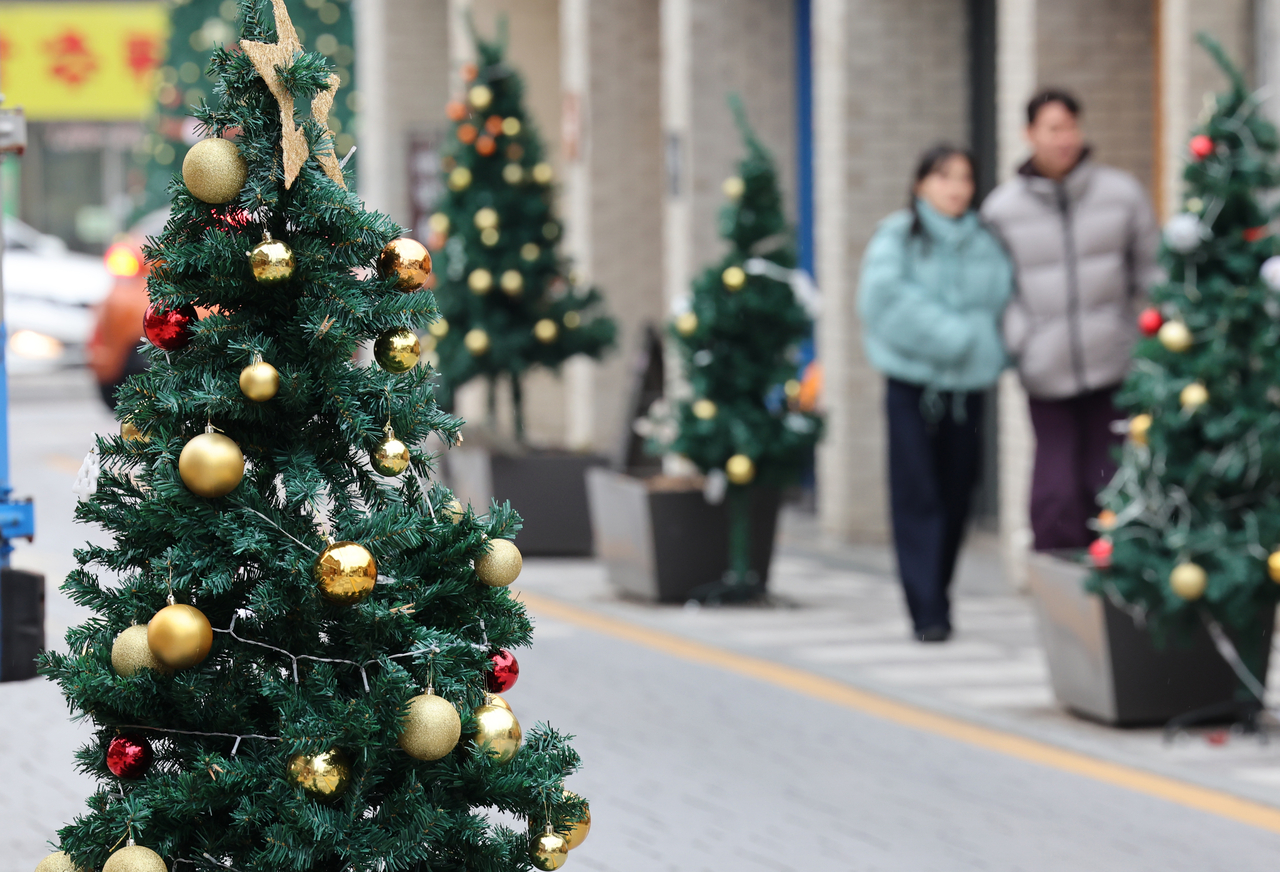 A couple strolls along a street decorated with Christmas trees in Gwangju on Friday. (Yonhap)