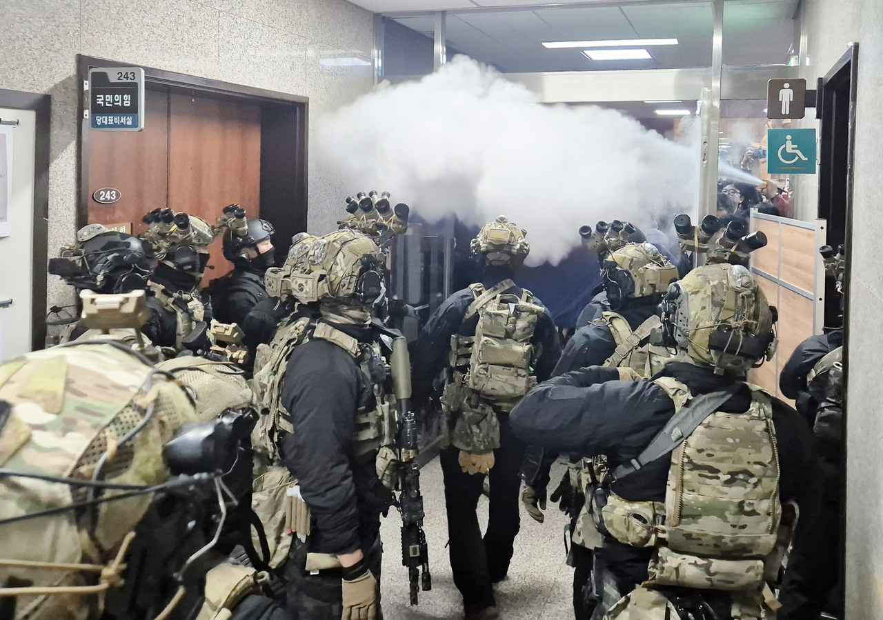 Martial law forces attempting to reach the main chamber of the National Assembly on Dec. 3 confront a group of parliamentary staff and reporters blocking their entry with extinguishers and partitions. (Yonhap)