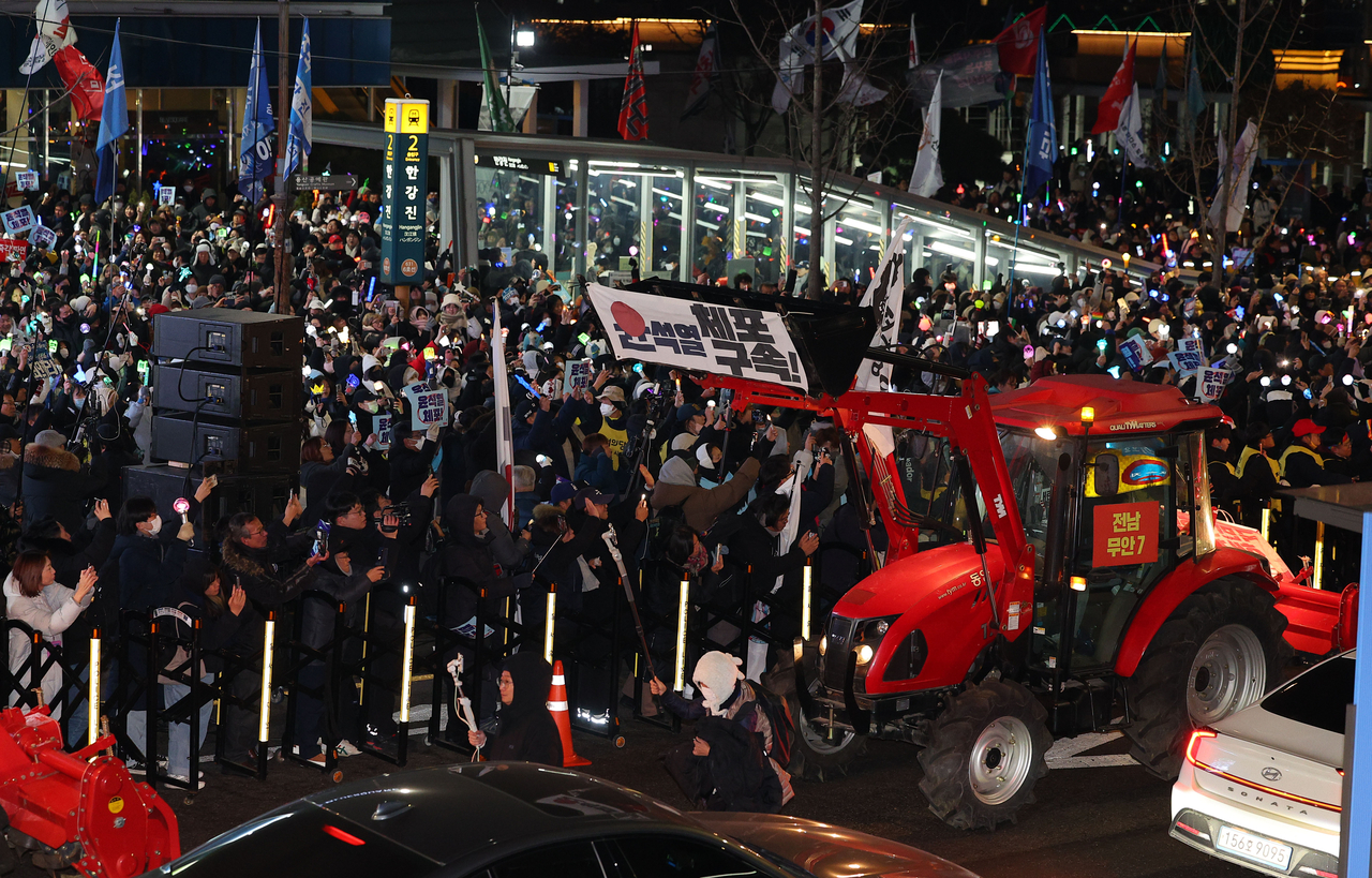 Protestor calling for President Yoon Suk Yeol's arrest are cheering at one of the tractors driven by the farmers' group, who joined them from rural parts of the country in a Sunday demonstration near the presidential office in Yongsan-gu, Seoul. (Yonhap)