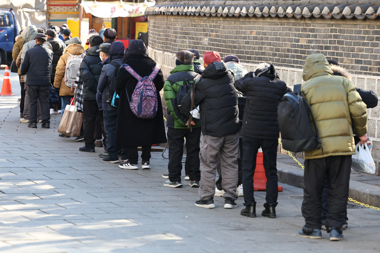 Senior citizens line up to receive free meals at Wongaksa in Tapgol Park, Jongno, central Seoul, Tuesday. (Yonhap)