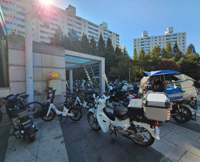 Han waits for a delivery order at a motorcycle parking lot near Wangsimni Square, Seongdong-gu (Choi Jae-hee / The Korea Herald)