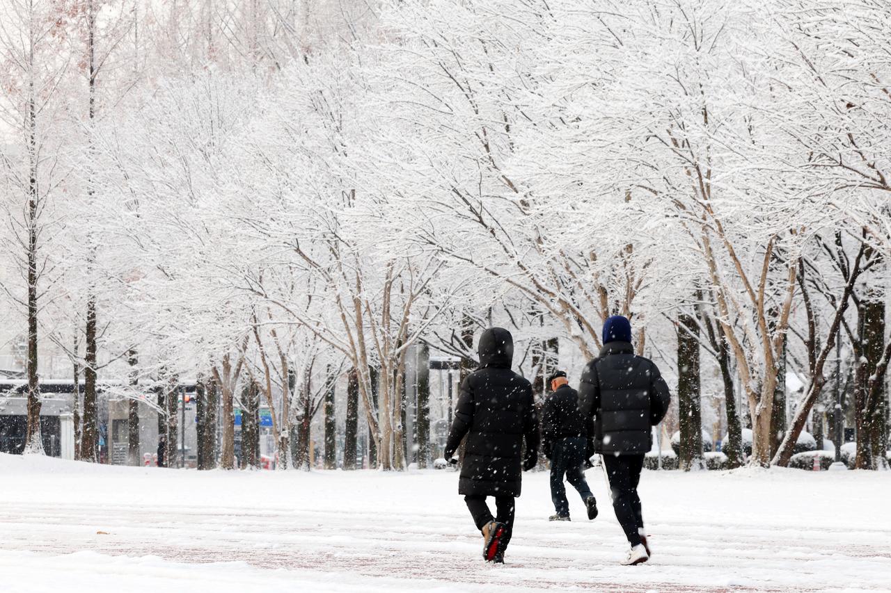 People are taking a walk on a snow-covered trail at the Chonnam National University in Gwangju on Saturday. (Yonhap)