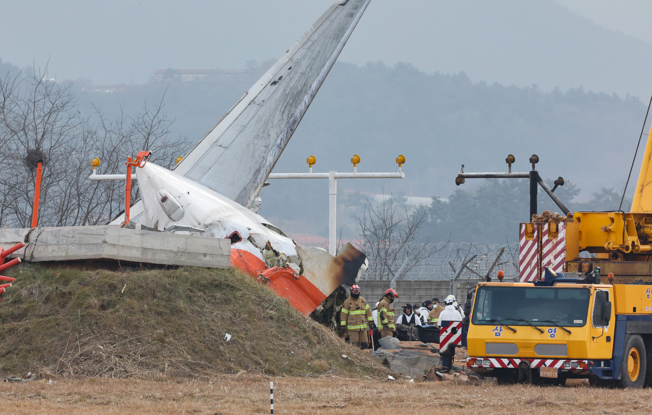 Firefighters carry out search operations at Muan International Airport in the southwestern county of Muan on Monday after a Jeju Air passenger plane with 181 people aboard crashed the previous day. (Yonhap)