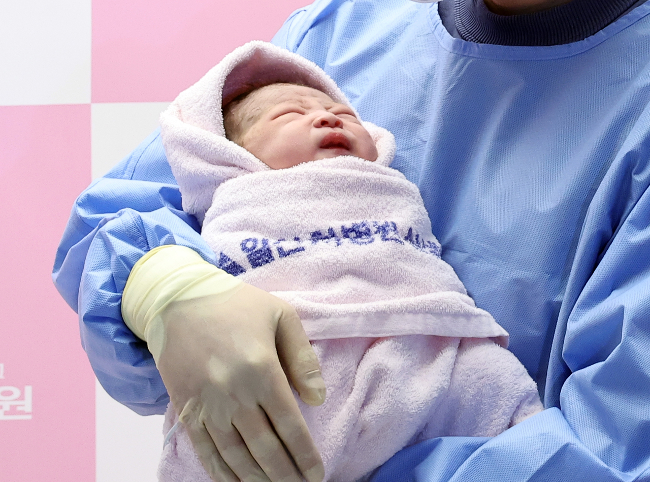 A baby born on Wednesday, New Year's Day 2025, is held by his father at a hospital in Goyang, Gyeonggi Province. (Yonhap)