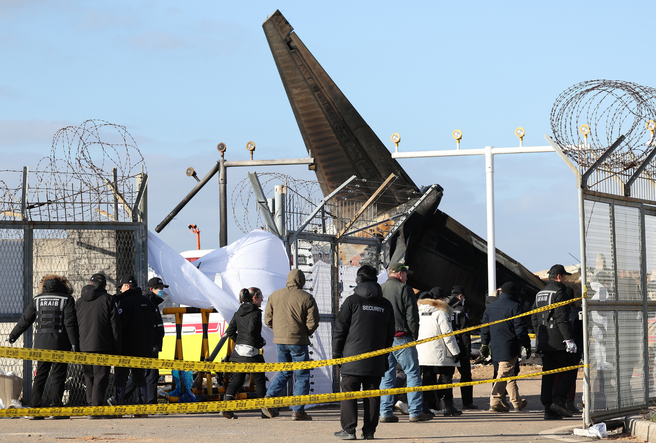 Investigators conduct an on-site investigation at the scene of the Jeju Air crash at Muan International Airport in southwestern South Korea on Tuesday (Yonhap)