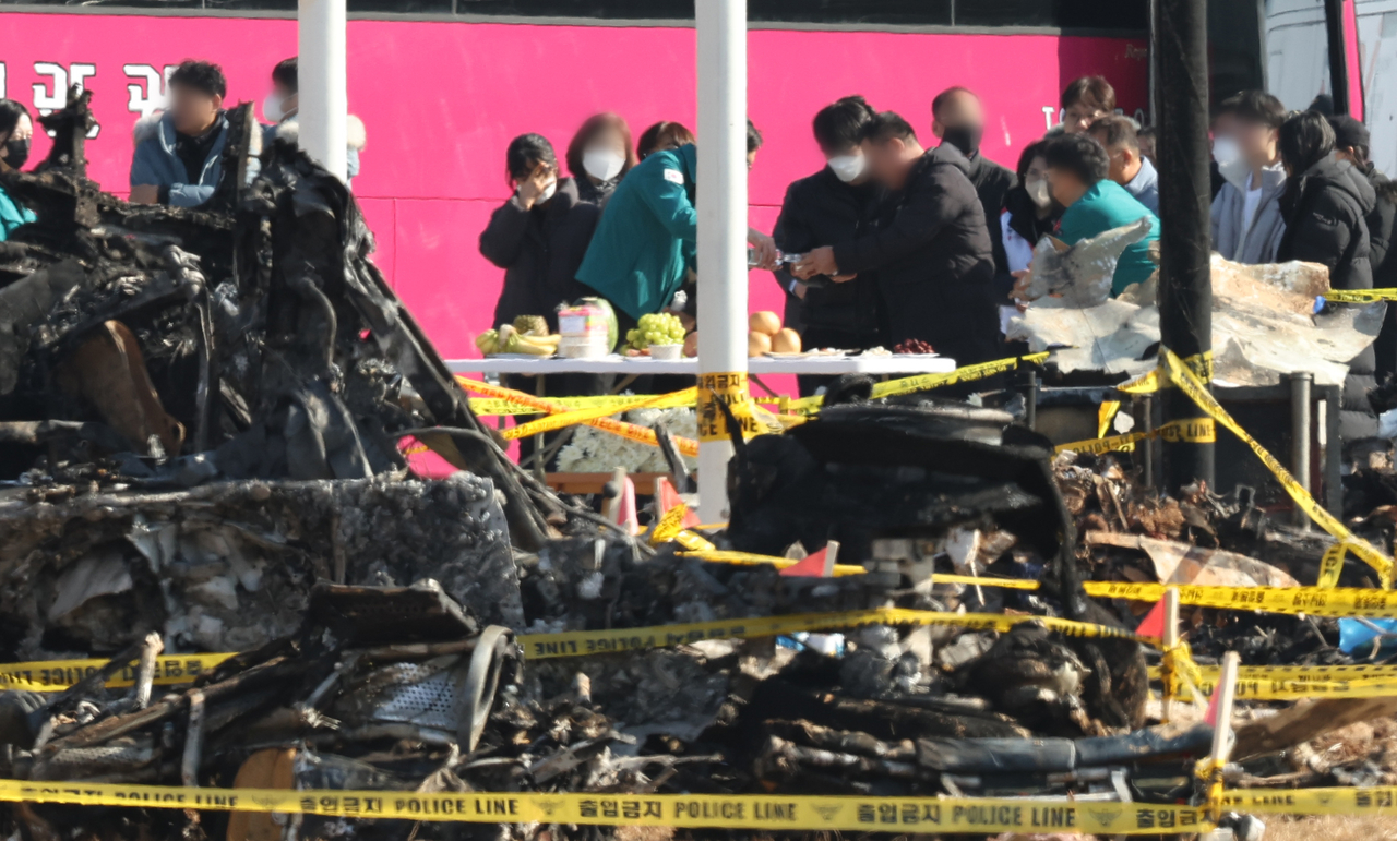 Bereaved family members at the scene of the Jeju Air crash at Muan International Airport in South Jeolla Province set up a table for a mournful celebration of the new year, Wednesday. (Yonhap)