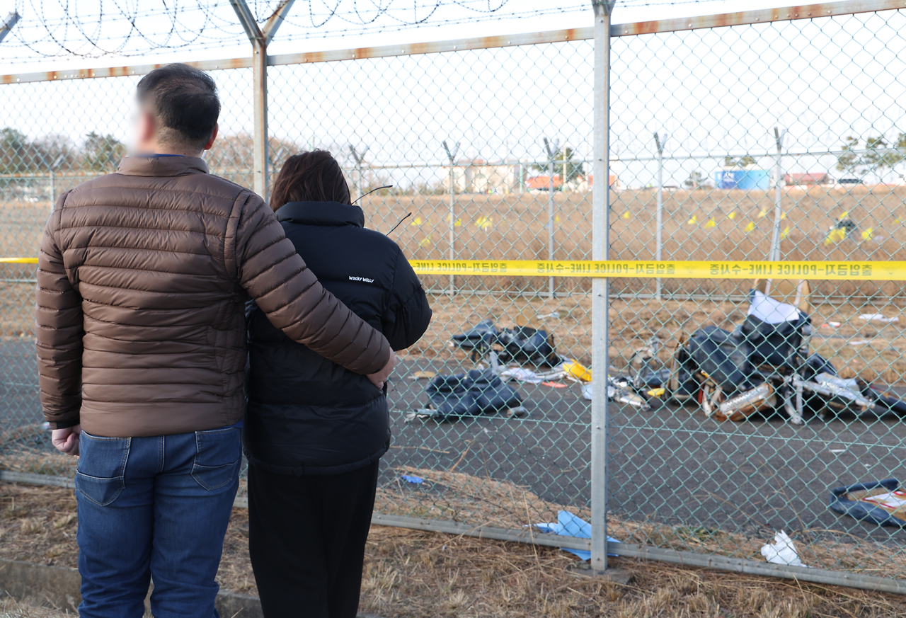 Bereaved family members of the Jeju Air plane crash that killed 179 people on Dec. 29 at Muan International Airport in Muan, South Jeolla Province, look on at the scene of the accident, Tuesday. (Yonhap)