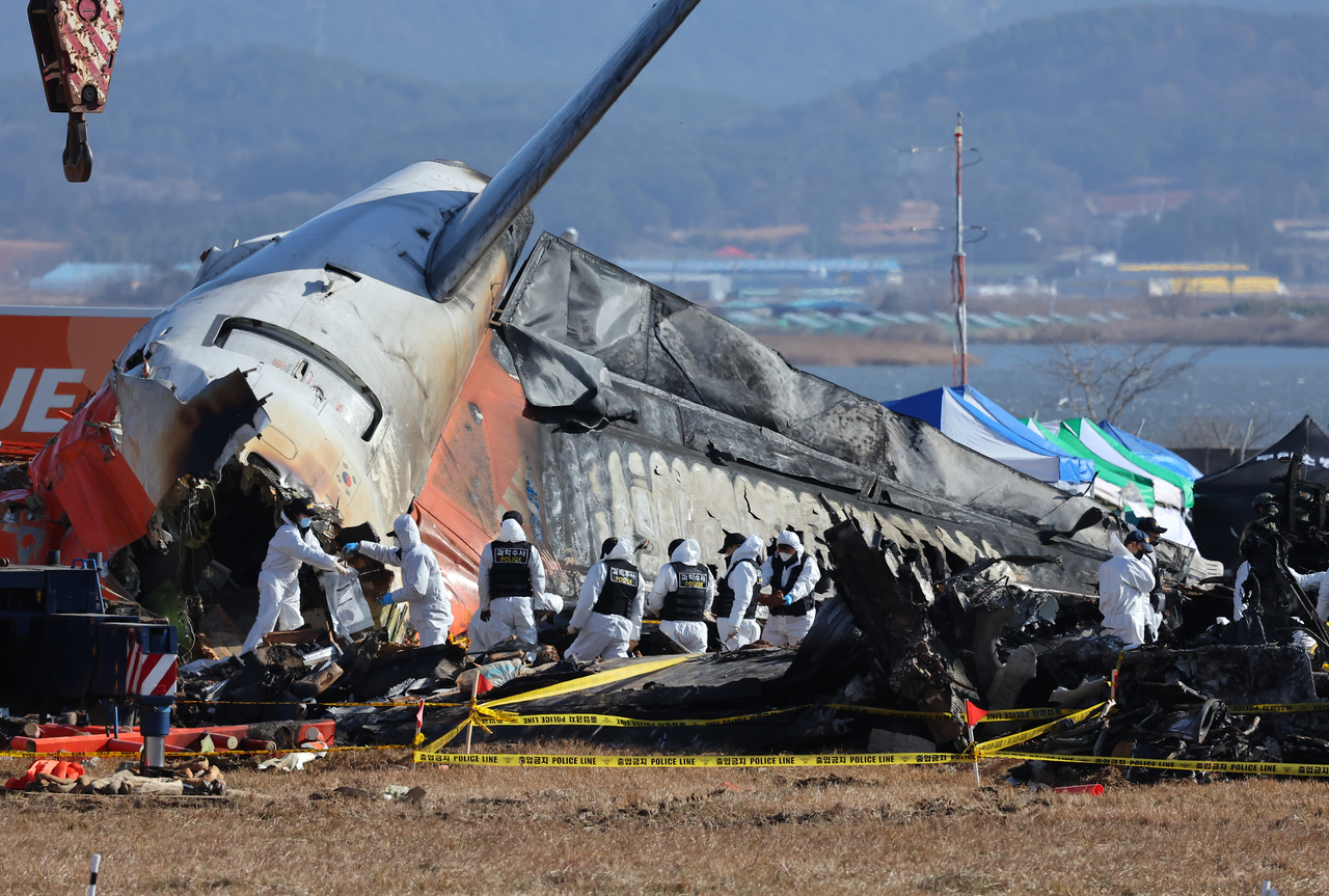 A police forensic team conducts an on-site investigation at the scene of the Jeju Air crash at Muan International Airport in southwestern South Korea on Tuesday. (Yonhap)