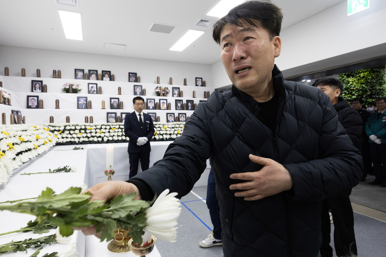 Park Han-shin, who represents the bereaved families of Sunday's Jeju Air crash, lays a flower at a memorial altar near Muan International Airport in South Jeolla Province on Tuesday. (Yonhap)