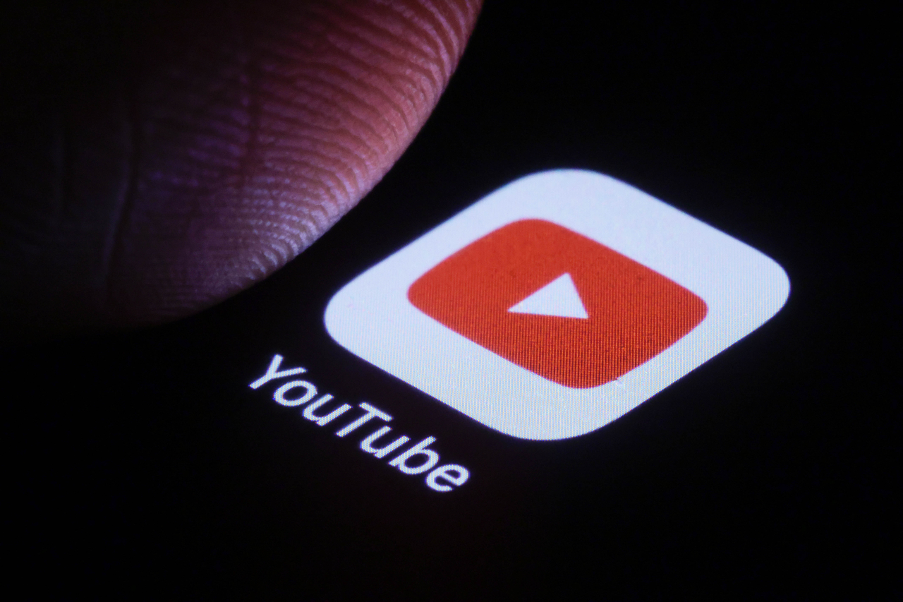The logo of YouTube can be seen next to a finger on a smartphone. (GettyImages)