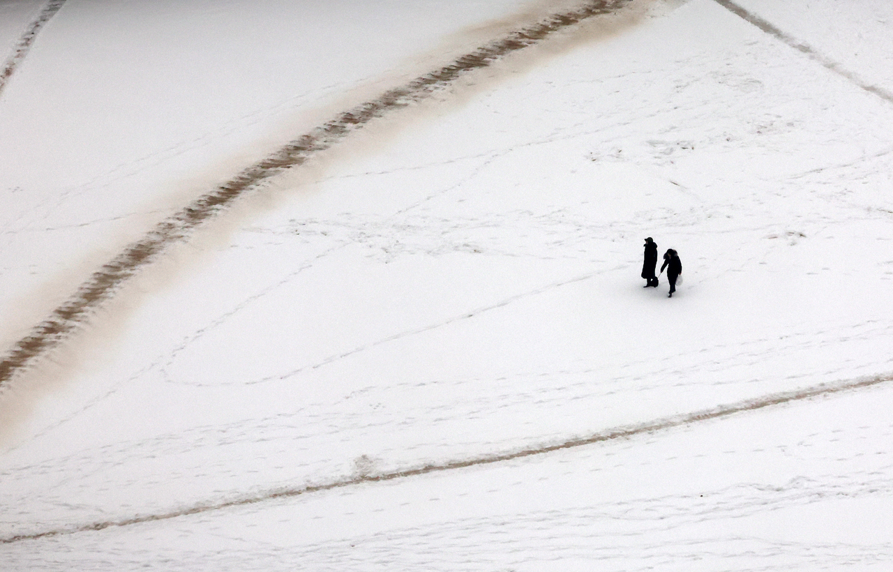 Visitors stroll through the snow-covered grounds of Gyeongbokgung in Jongno-gu, Seoul, on Sunday morning following an overnight snowfall. (Newsis)