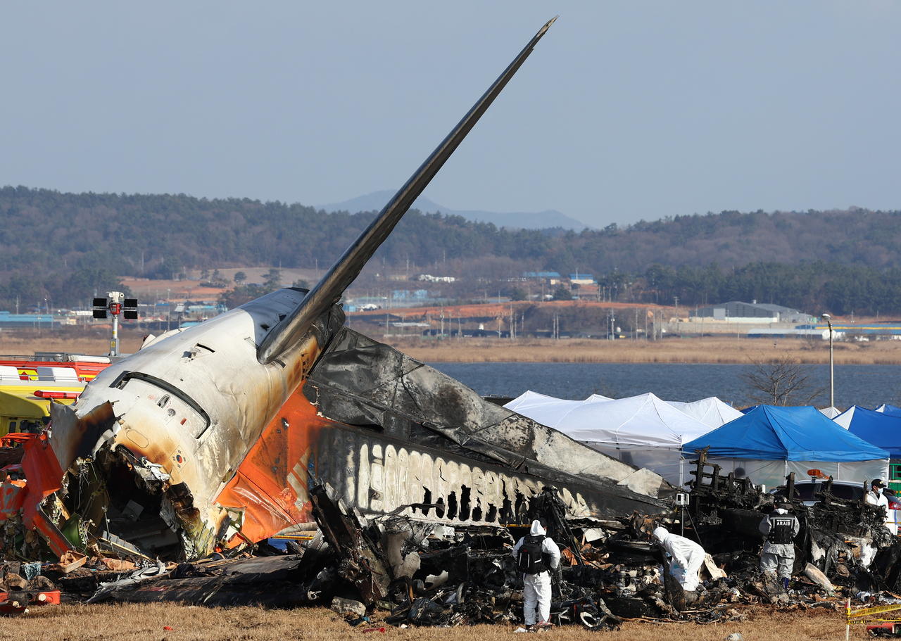 Police forensic investigators work at the scene of the Jeju Air passenger plane crash at Muan International Airport in South Jeolla Province, Monday afternoon. (Yonhap)