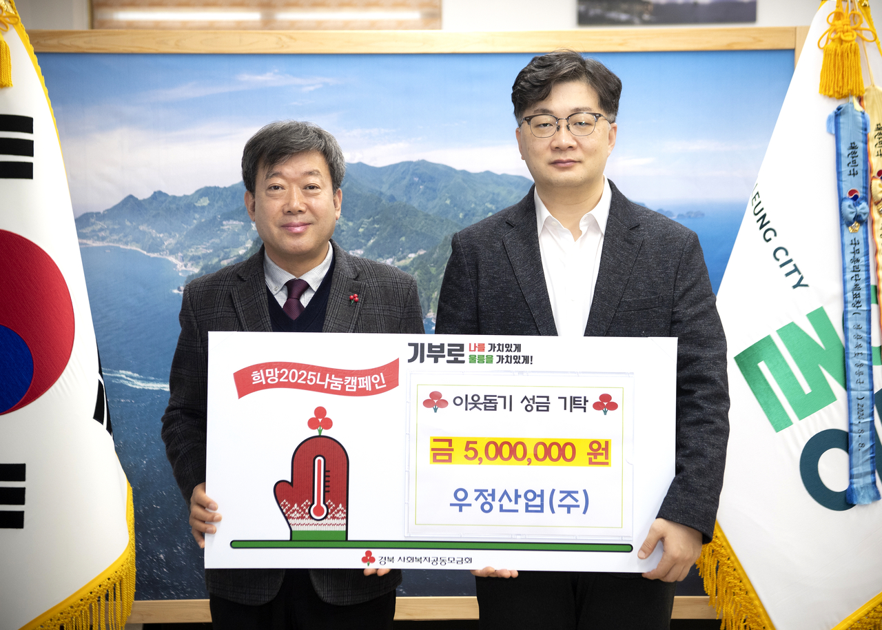 한익현(사진오른쪽) 우정산업대표가 남한권 울릉군수에게  불우이웃돕기 성금 500만원을  전달하고 있다(울릉군 제공)
