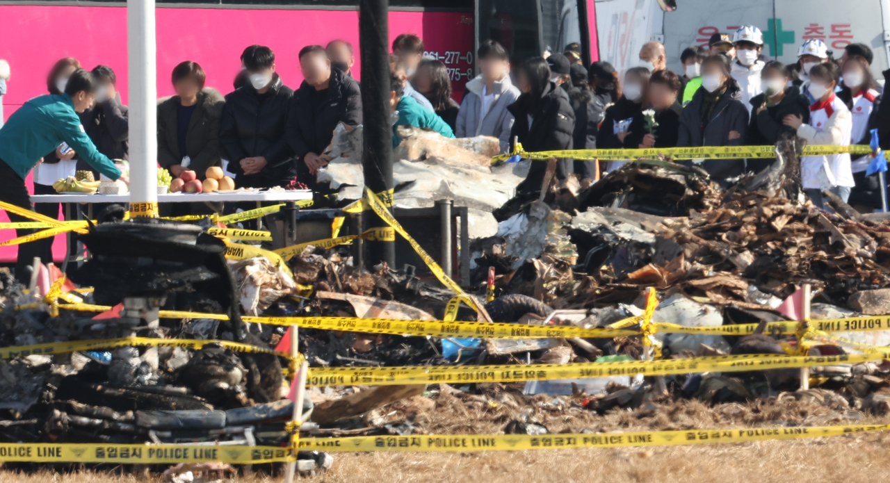 1일 전남 무안군 무안국제공항 제주항공 여객기 참사 현장을 찾은 탑승객 유가족들이 간소한 상을 차려두고 희생자들에게 새해 인사를 하며 오열하고 있다. [연합]