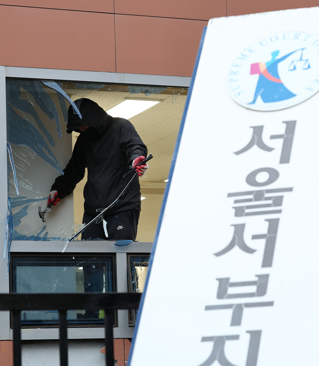 19일 윤석열 대통령 구속 소식을 들은 일부 윤 대통령 지지자들이 불법폭력사태를 일으킨 서울 마포구 서울서부지방법원에서 한 작업자가 복구 작업을 하고 있다. [연합]>