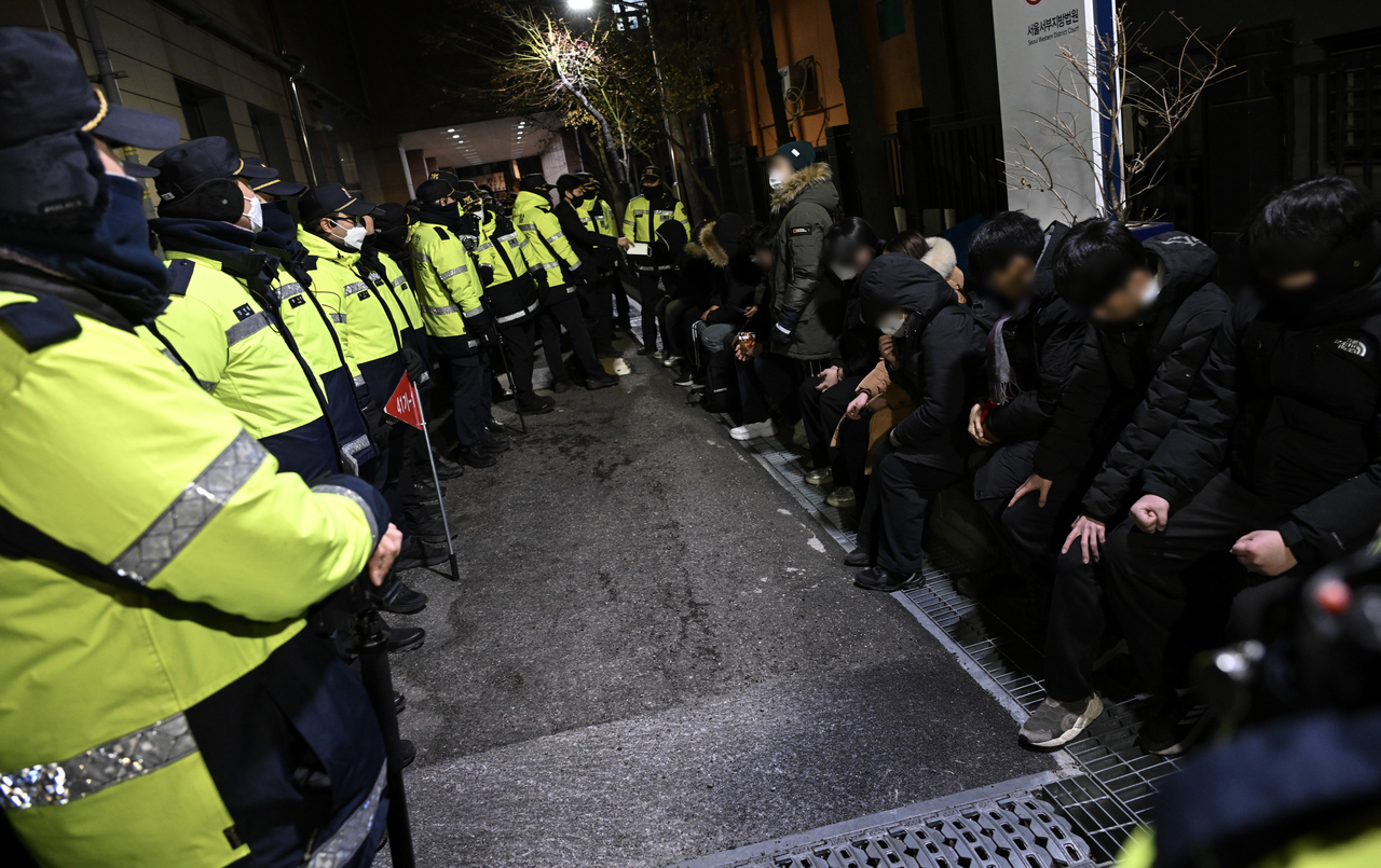 Supporters of President Yoon Suk Yeol, detained for their involvement in violent protests, are detained by police outside the Seoul Western District Court in Mapo-gu, Seoul, Sunday. (Yonhap)