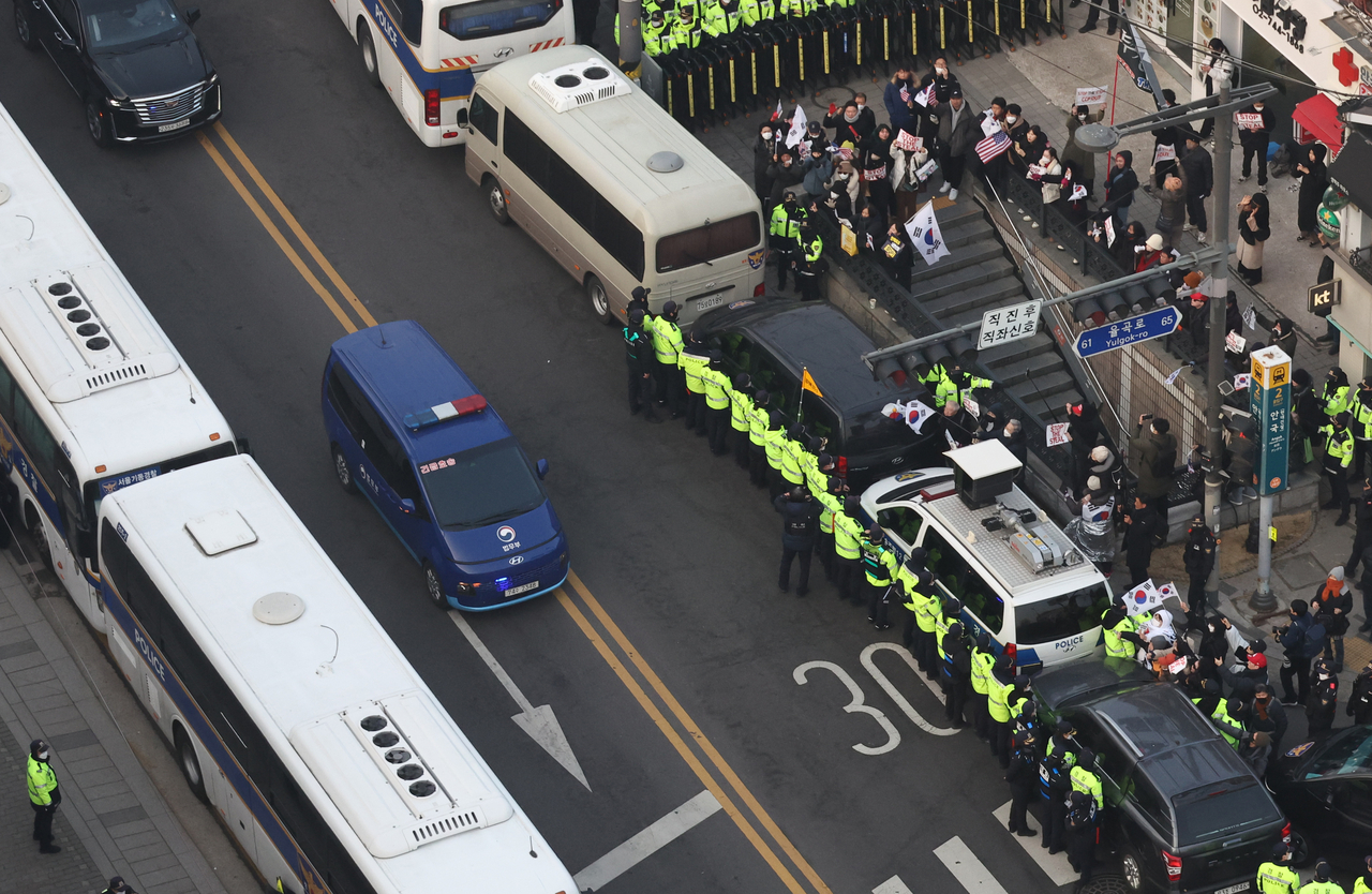 A justice ministry vehicle (center, blue) carrying arrested President Yoon Suk Yeol drives on a road en route to the Constitutional Court in Seoul on Tuesday, as Yoon will attend the third hearing of his impeachment trial in connection with his short-lived imposition of martial law in December. (Yonhap)