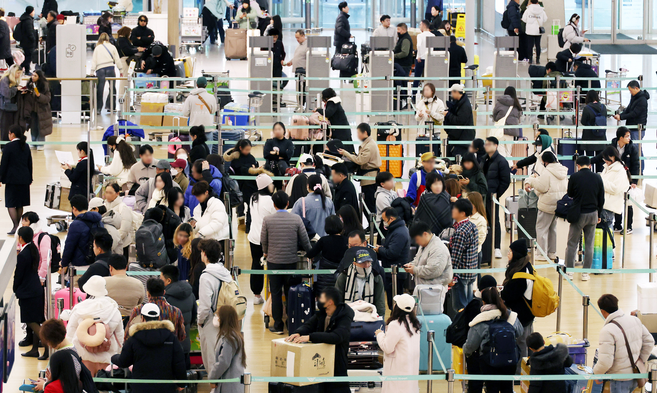 Passengers wait in line at a check-in counter at Incheon International Airport Terminal 1, on Dec. 23. (Newsis)