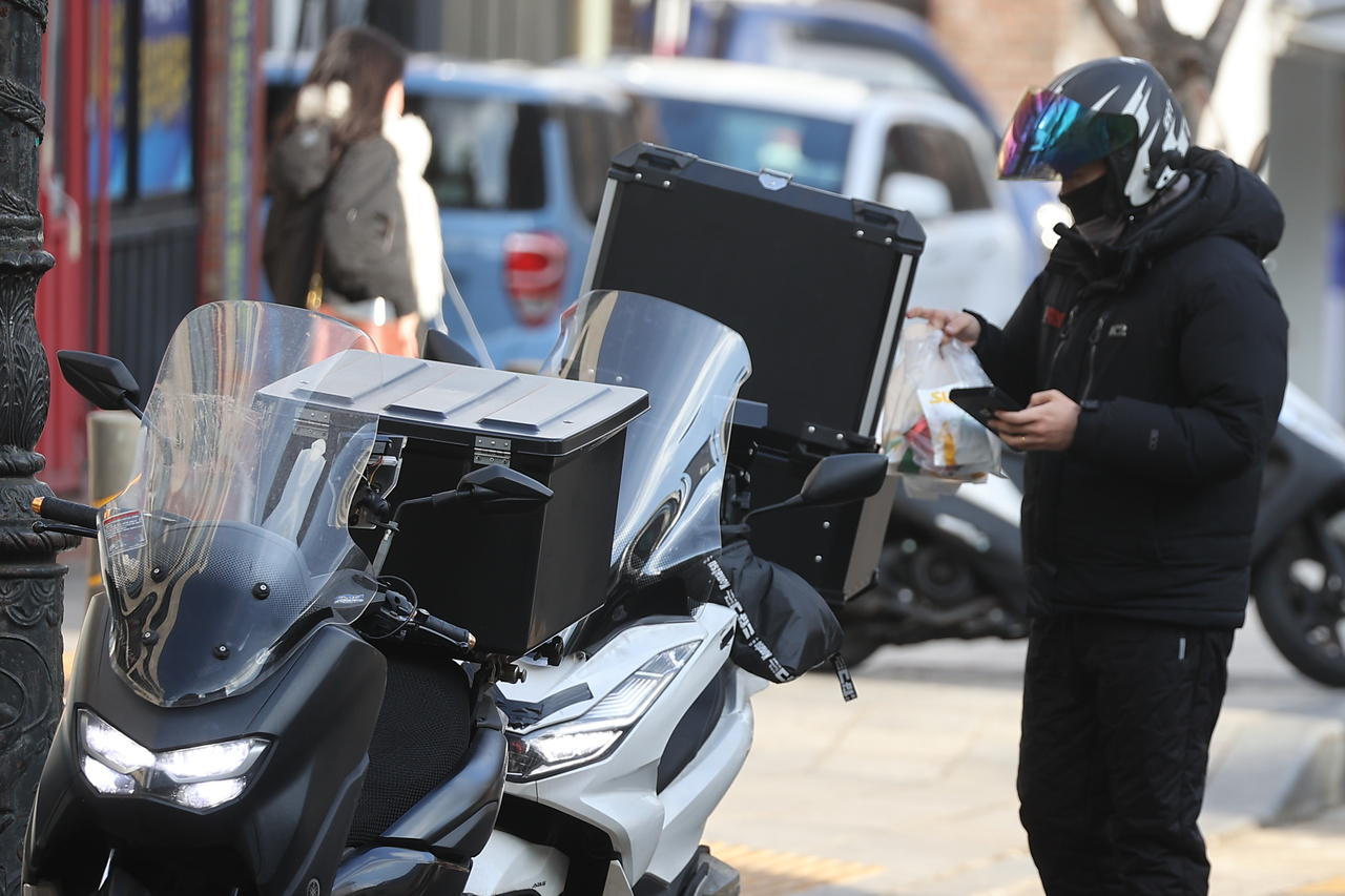 A delivery worker carries food orders in Seoul on Jan. 7. (Yonhap)