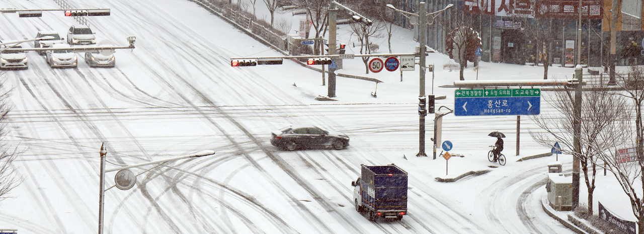 Traffic slows to a crawl in Hyodong-dong, Wansan-gu, Jeonju, as Jeollabuk-do Province, South Korea, faces heavy snowfall under a provincial snow alert on Tuesday. (Yonhap)